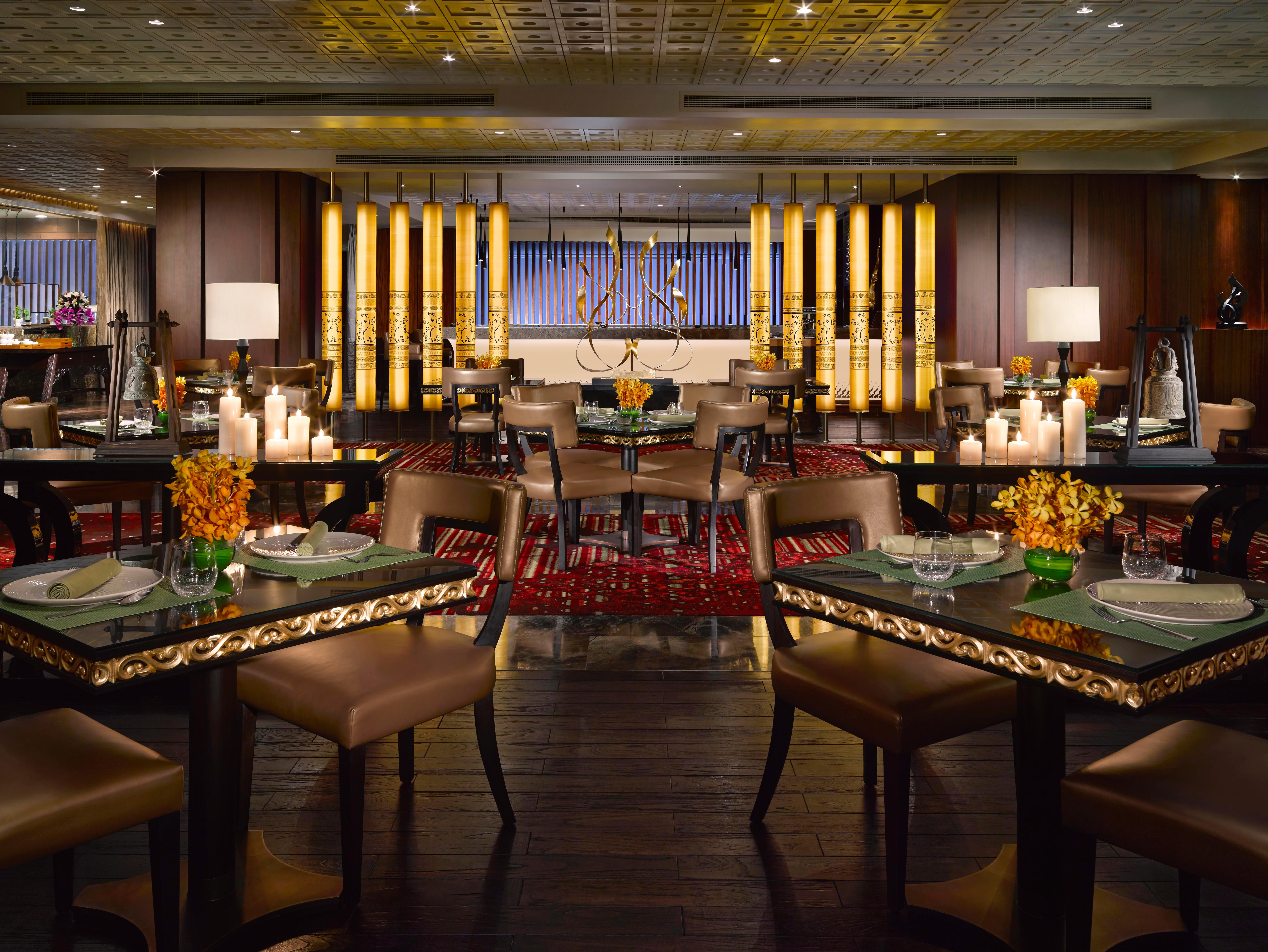 Dusit Thani Abu Dhabi Exterior photo The photo shows an elegant restaurant interior featuring a modern design. The space is well-lit, with a warm and inviting ambiance. There are several tables arranged neatly, each adorned with decorative elements like flowers and candles. The seating 