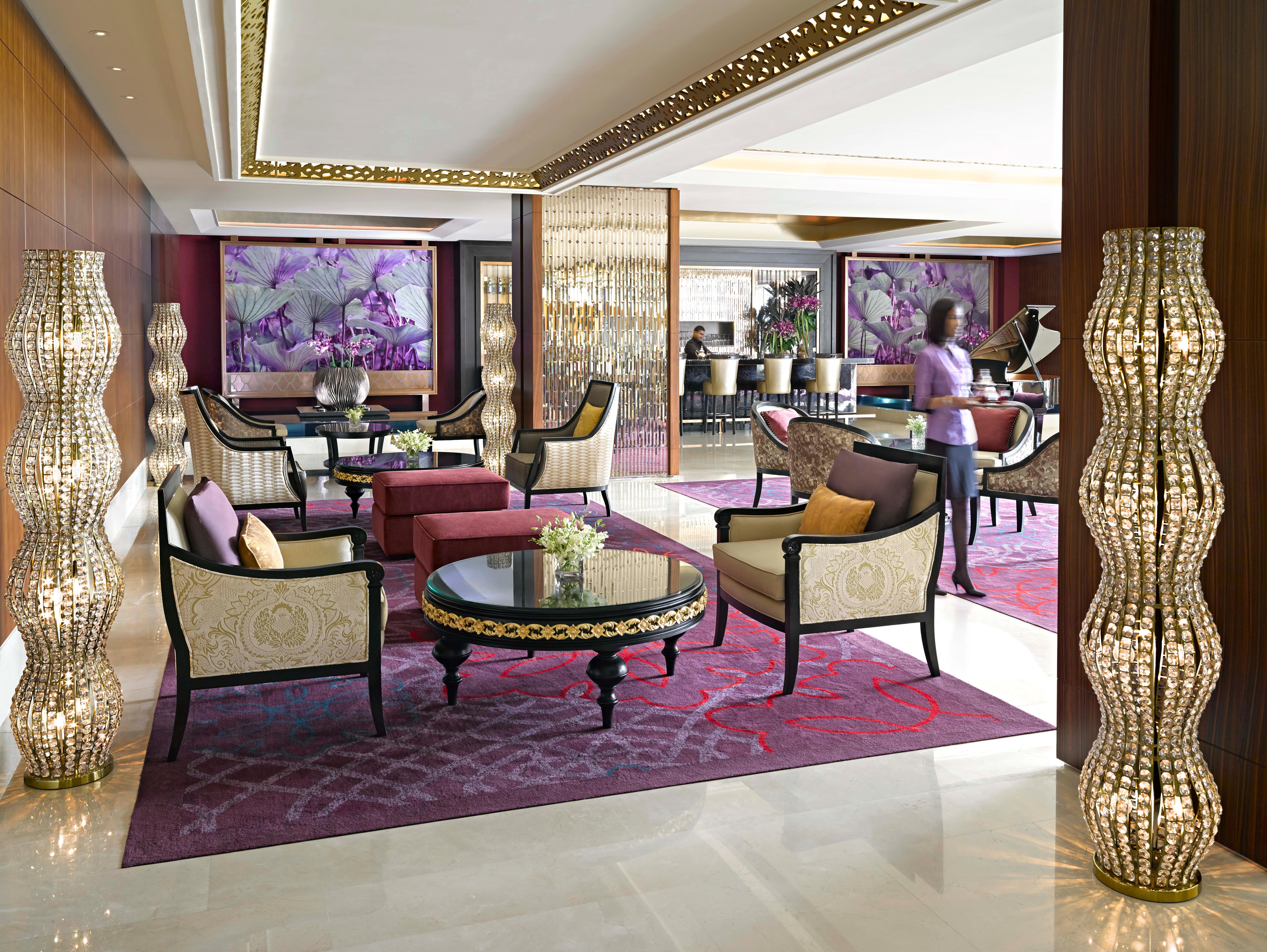 Dusit Thani Abu Dhabi Exterior photo The photo depicts an elegant and stylish lounge area, possibly within a hotel or a luxury venue. The space features plush seating arrangements with ornate chairs and sofas arranged around a circular coffee table. The decor includes decorative light f