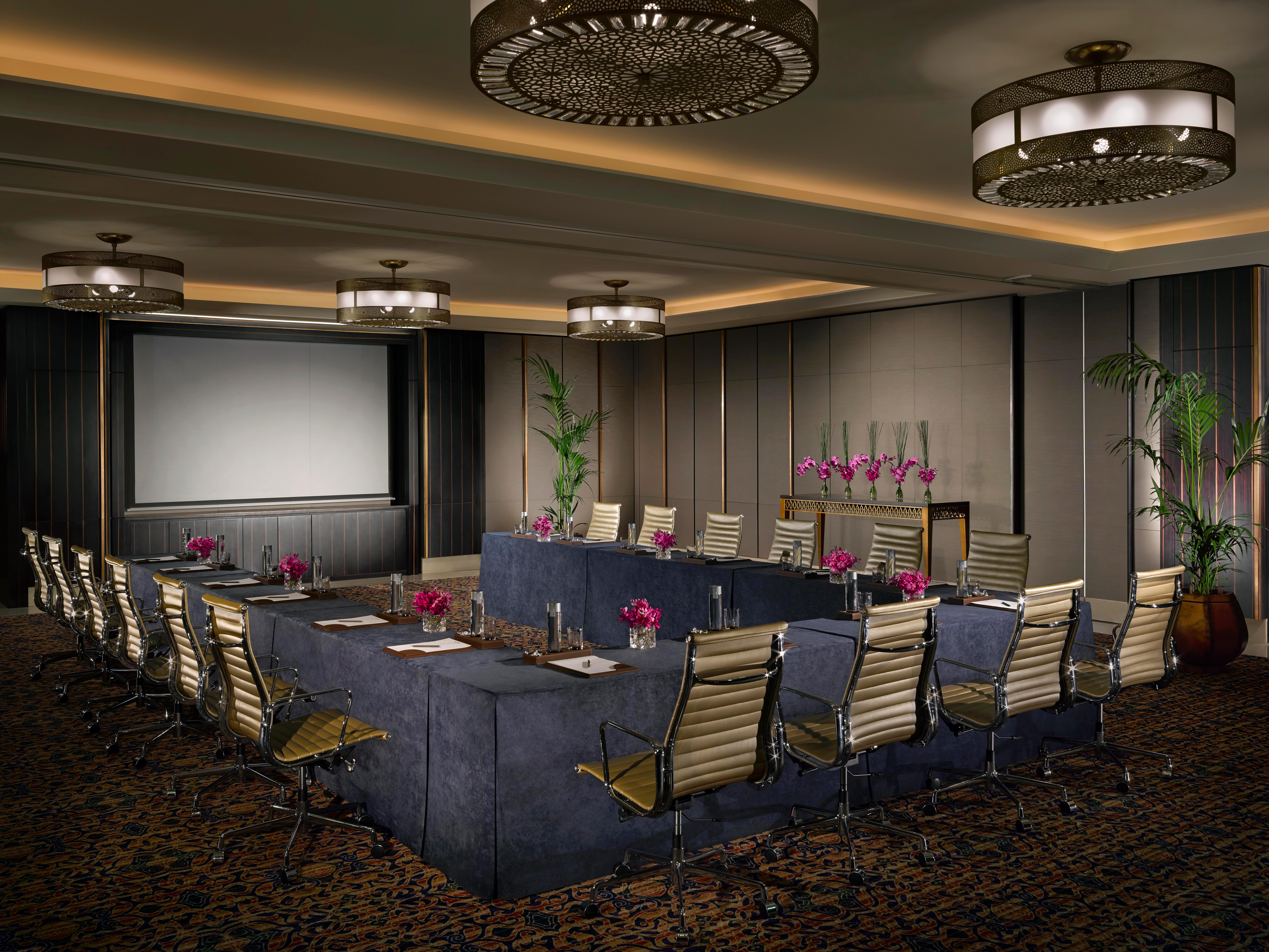 Dusit Thani Abu Dhabi Exterior photo The photo depicts a well-designed conference room. It features a large, rectangular table arranged with several ergonomic chairs around it. The room is illuminated by stylish overhead light fixtures, and there is a large screen at one end for present