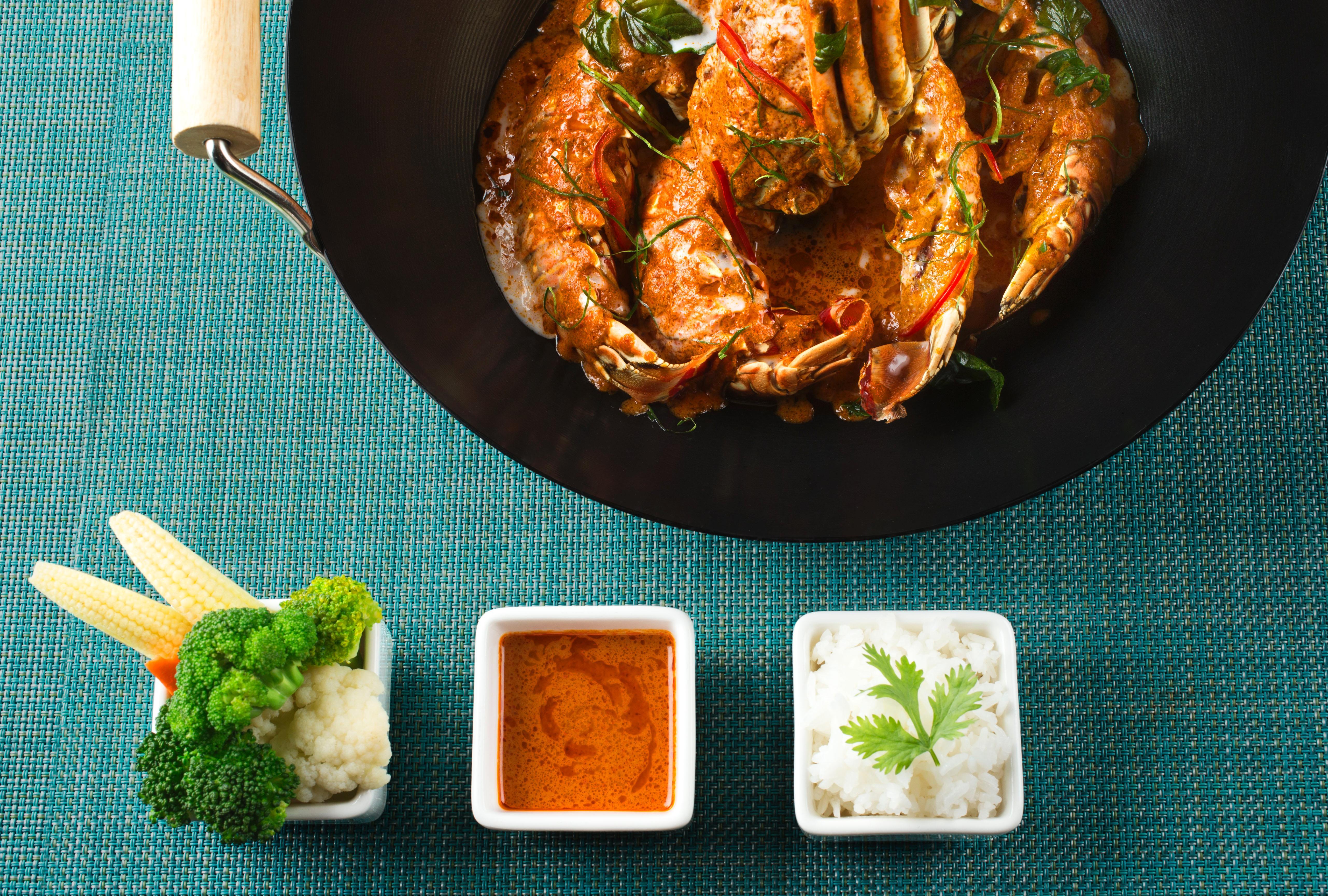 Dusit Thani Abu Dhabi Exterior photo The photo features a colorful dish of cooked shrimp, presented in a black frying pan. The shrimp appear to be well-seasoned, likely with herbs or spices, and are accompanied by sliced vegetables. Next to the pan, there are three small bowls. One bowl